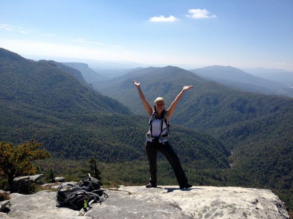 Woman posing for a picture on top of a mountain