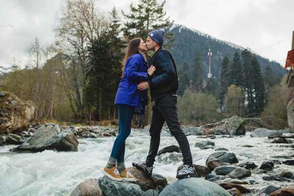 Man and woman kissing while standing on rocks in a stream