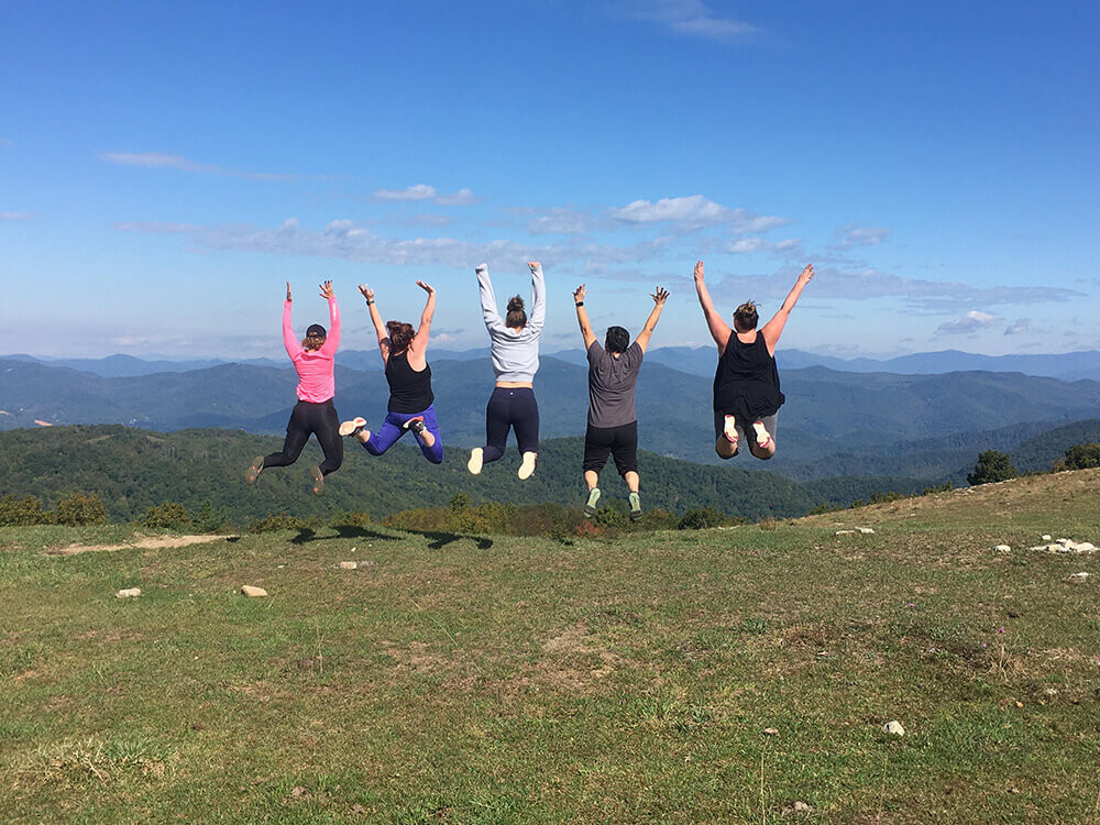 Group of Women Jumping in Front of a Mountain View