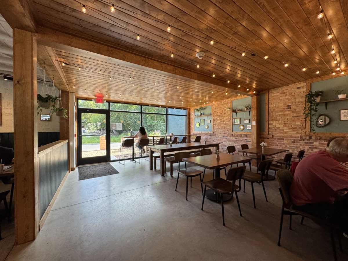 Interior of Ecusta Café near the Ecusta Trail, featuring warm wood ceilings, brick walls, cozy seating, and large windows overlooking the trail area.