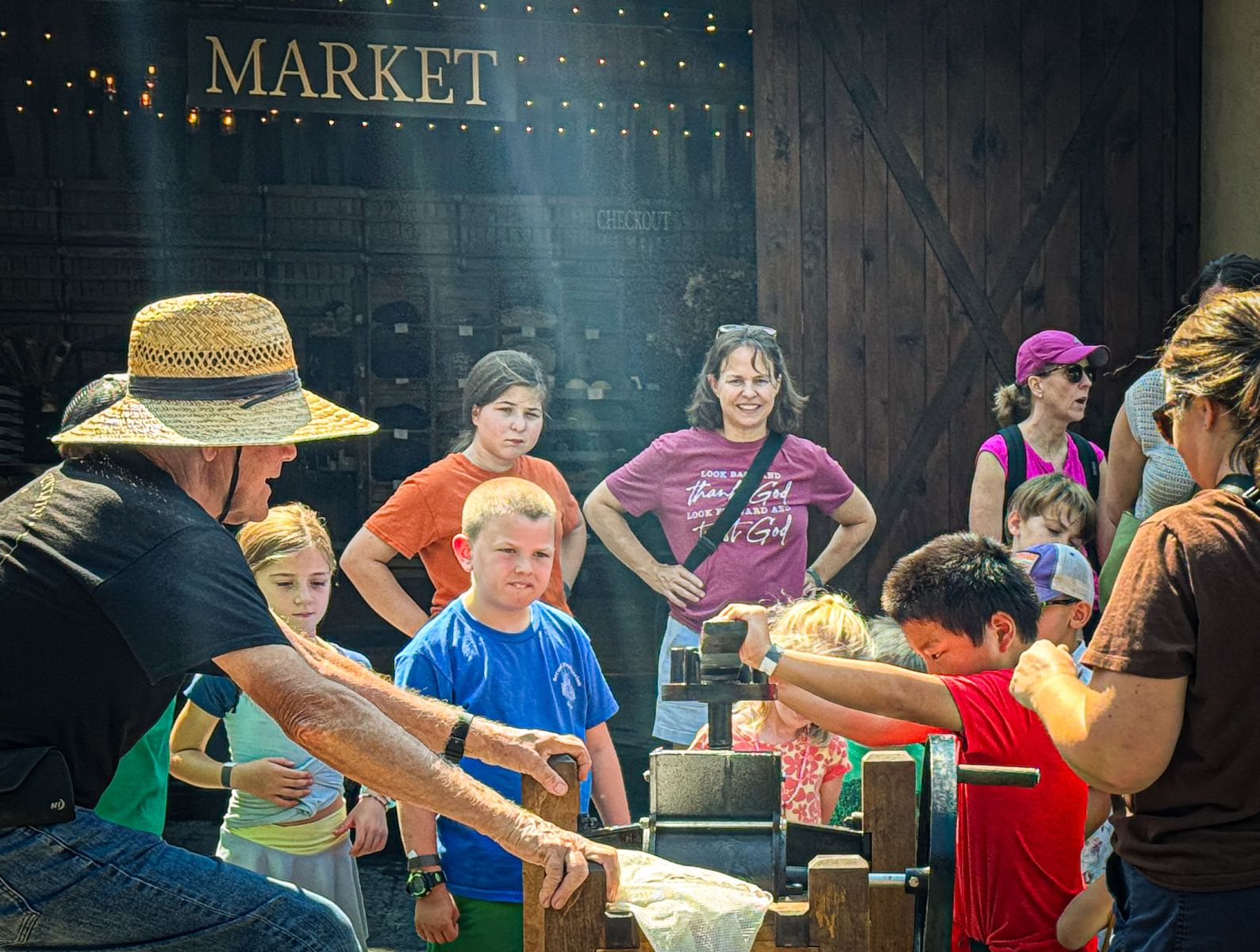 Kids surrounding an old-fashioned apple press.