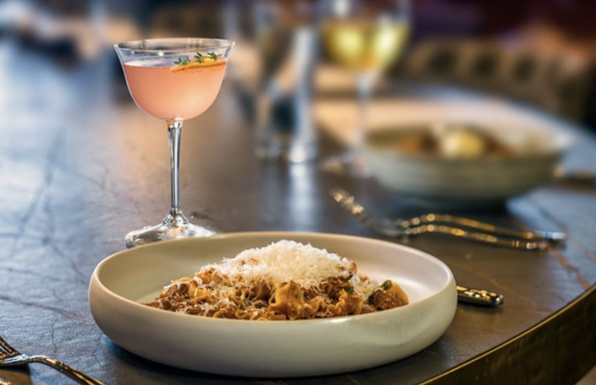 A cooked pasta dish with a cocktail in an elegant setting.