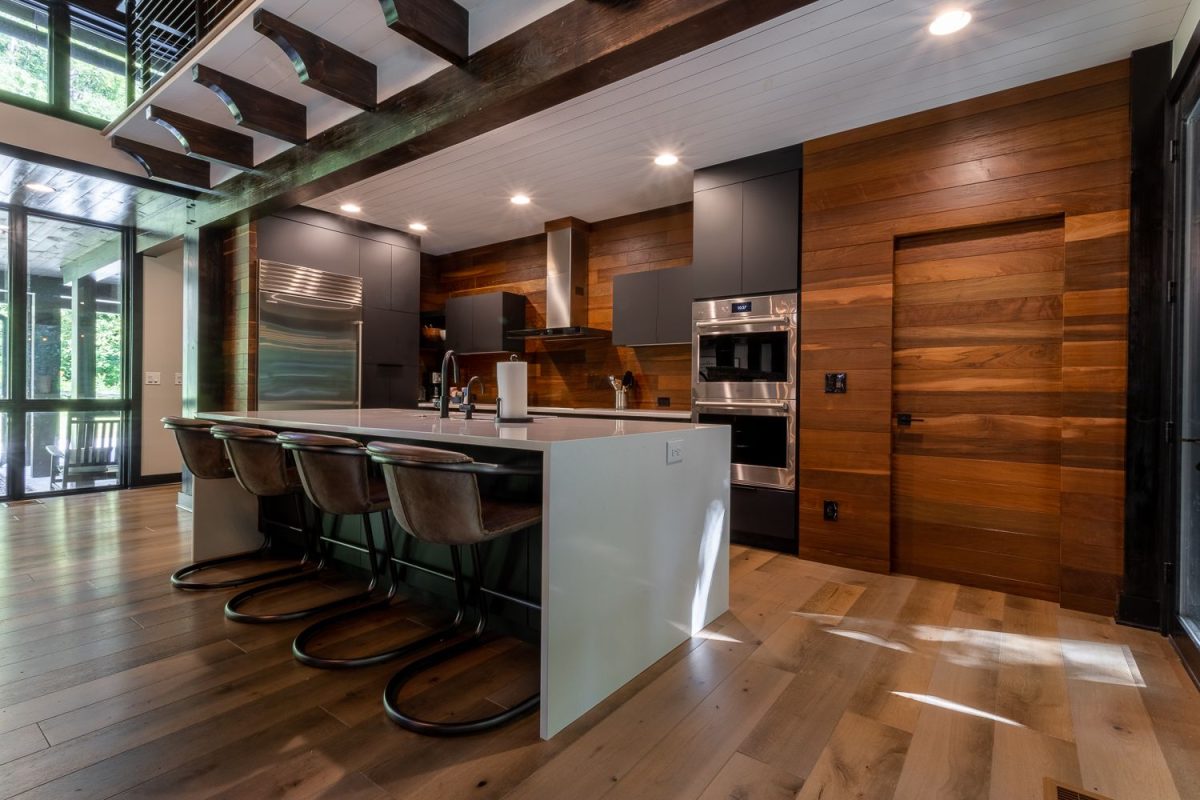 Professionally cleaned, modern mountain vacation rental kitchen with wood accents, stainless steel appliances, and a large island, prepared for guest arrival.