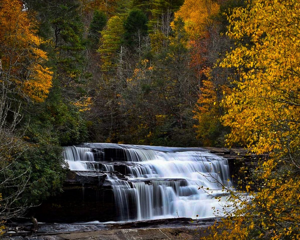 Waterfall surrounded by colorful fall foliage in Western North Carolina, a popular outdoor attraction near Asheville for group trips.