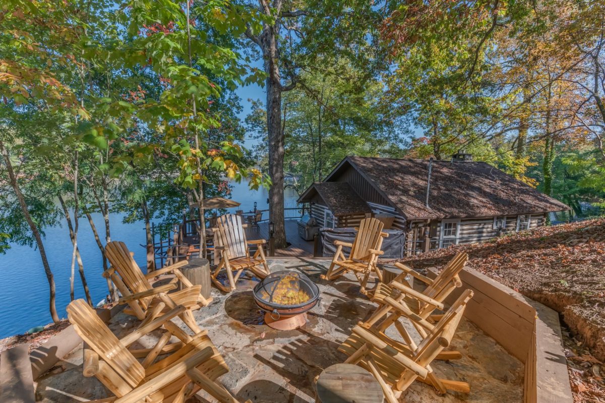 Adirondack chairs surrounding a fire pit overlooking Lake Lure beside the historic Cabin at White Oak Point vacation rental in Western North Carolina.