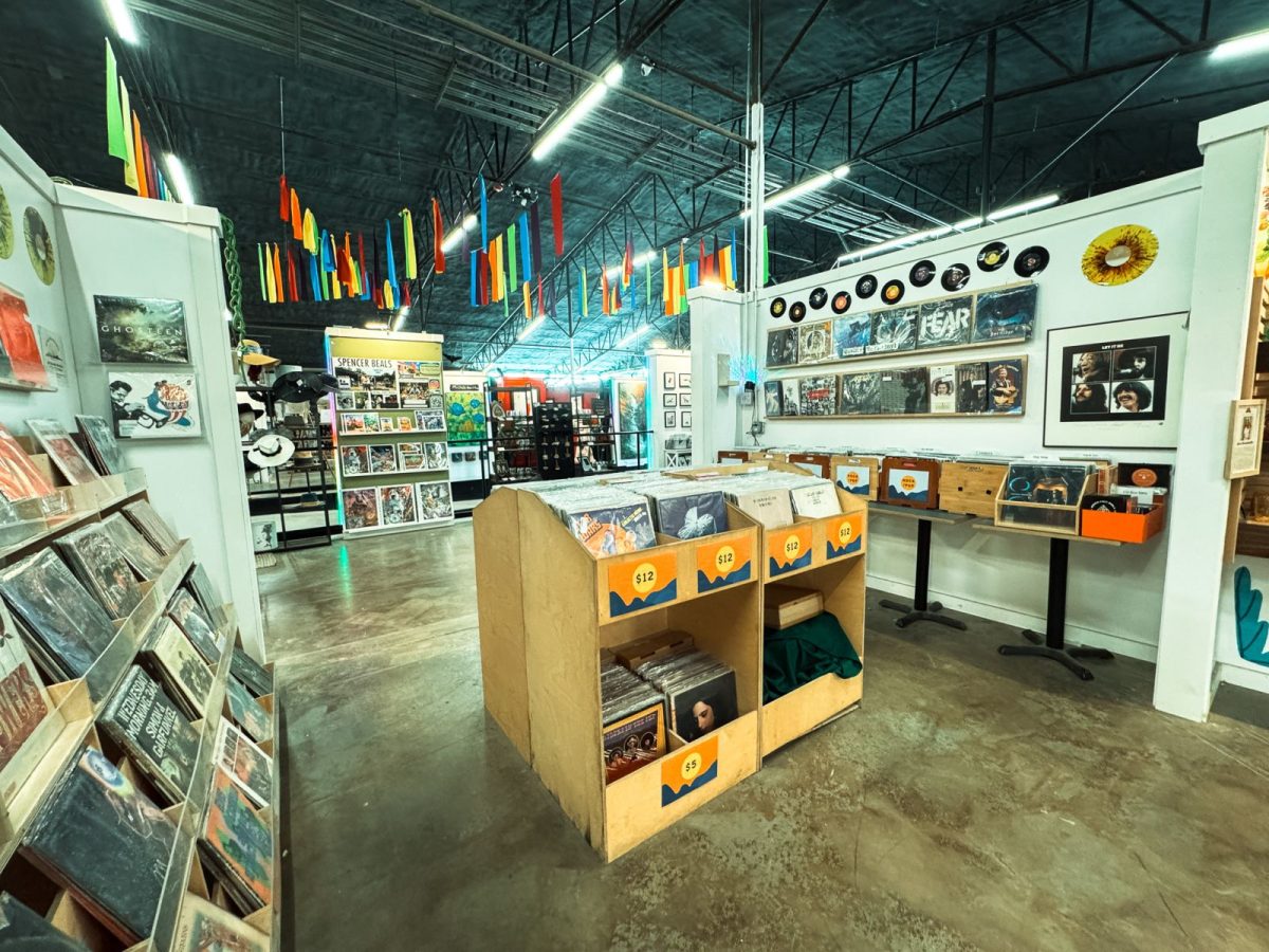 Interior view inside The Marquee in Asheville’s River Arts District featuring colorful hanging decor, vinyl record displays, local artwork, and vintage marketplace booths with albums and collectibles.