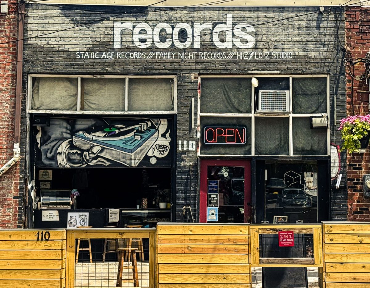 Exterior of Static Age Records in Asheville, North Carolina, featuring a black brick storefront, neon open sign, turntable mural artwork, and vintage independent record shop atmosphere.