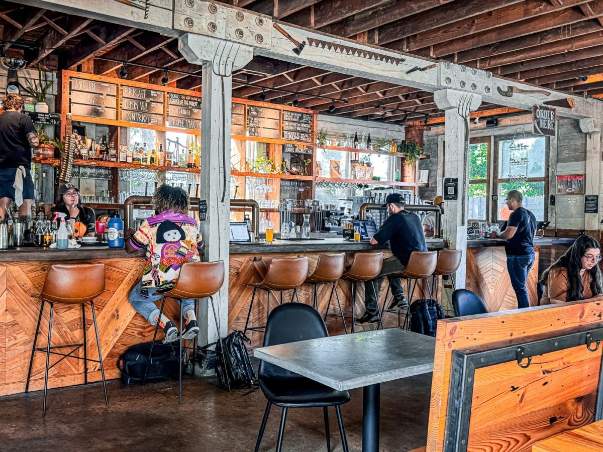 Guests enjoying craft beer and conversation inside Forestry Camp, a rustic brewery and restaurant in Asheville featuring reclaimed wood, exposed beams, communal seating, and a lively bar area.