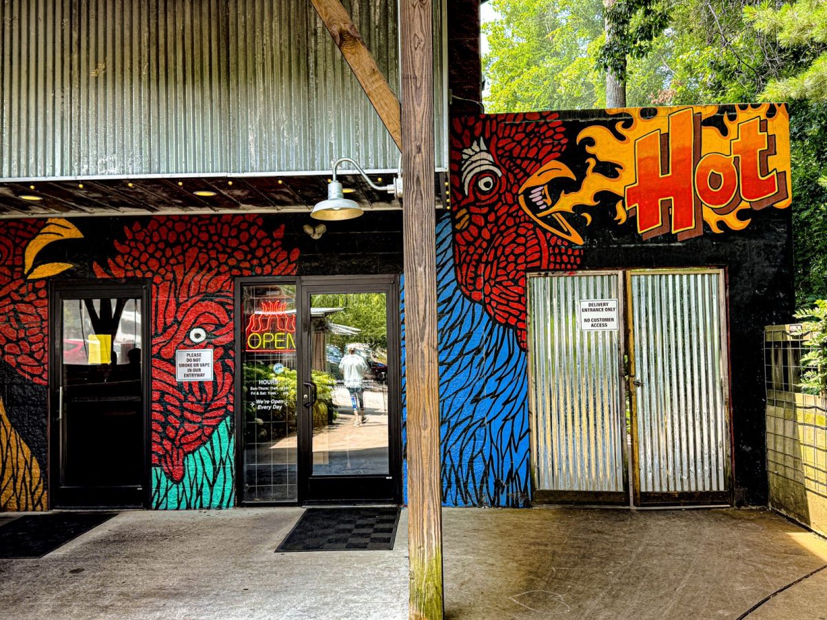 Colorful exterior mural at Rocky's Hot Chicken Shack in Asheville, North Carolina, featuring bold chicken artwork surrounding the restaurant's entrance.