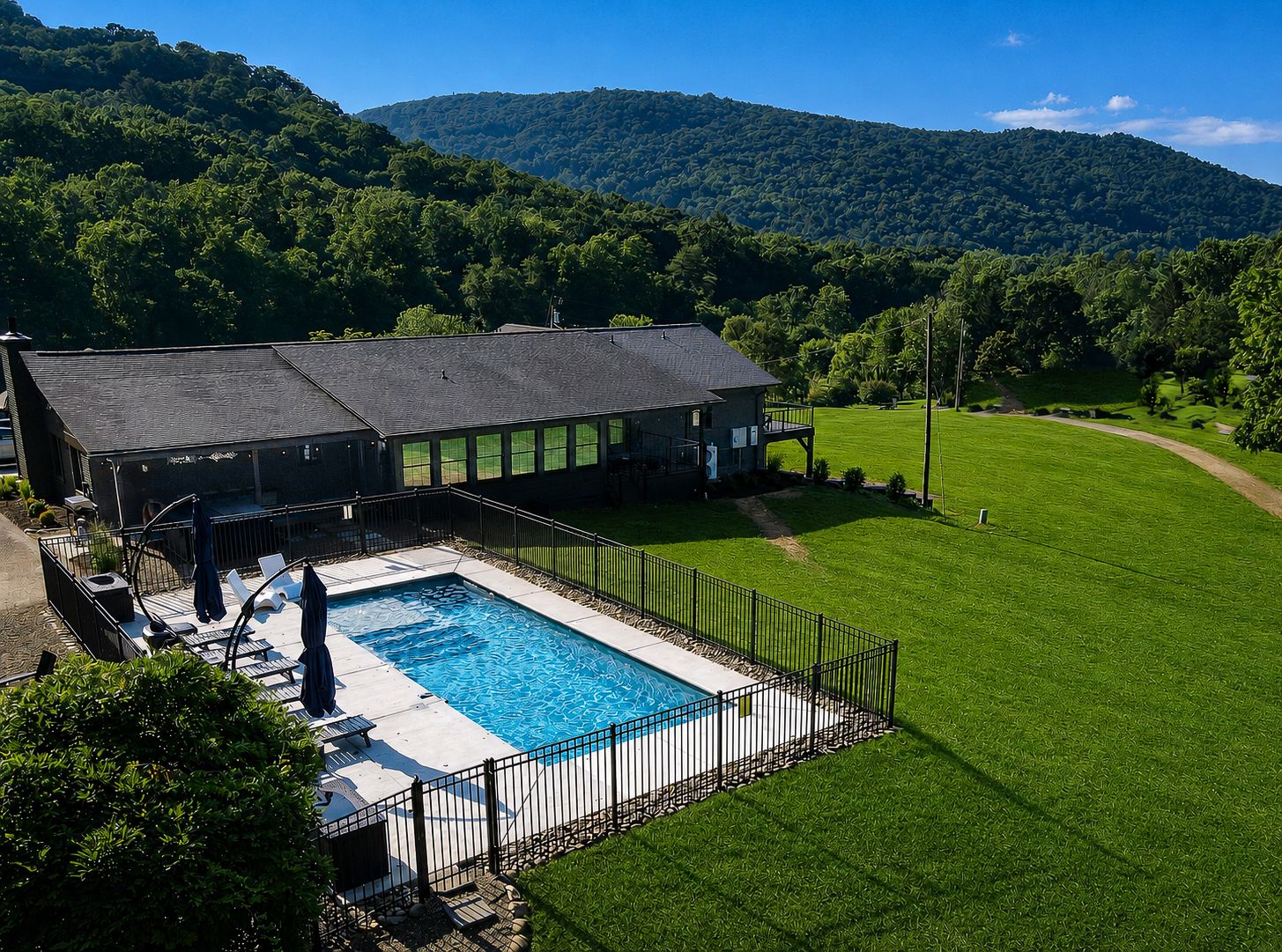 Aerial view of The Grange showcasing its private outdoor swimming pool, expansive green lawn, and beautiful Blue Ridge Mountain backdrop in Western North Carolina.
