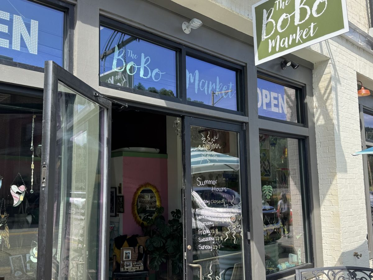 The entrance to The BoBo Market in downtown Marshall, North Carolina, with its hanging storefront sign, open front door, and bright display windows inviting visitors inside to browse locally made gifts, art, and specialty items.