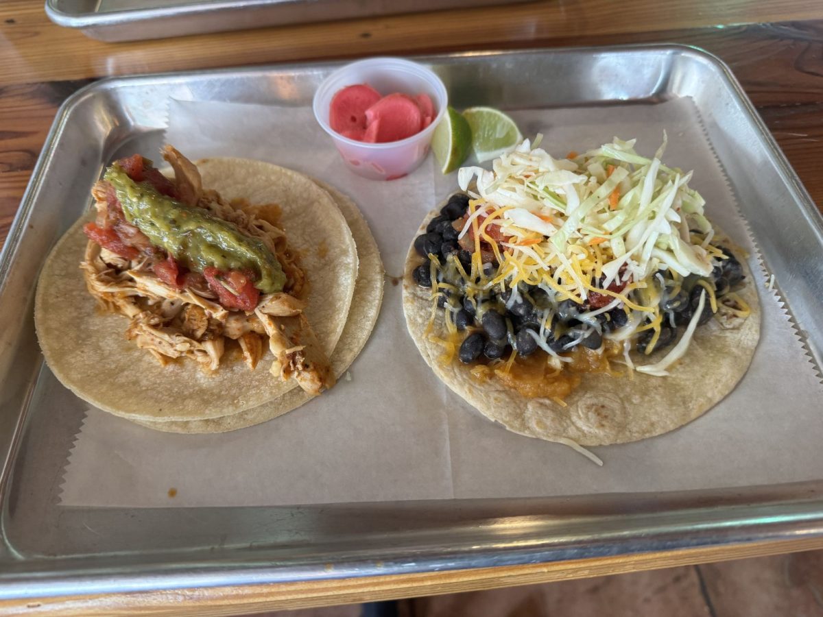 Two freshly made tacos from Star Taco in Marshall, NC, served on a metal tray with lime wedges and house-made pickled vegetables. One taco is topped with seasoned beef, lettuce, cheese, salsa, and spicy sauce, while the other features grilled chicken, lettuce, cherry tomatoes, and creamy sauce.