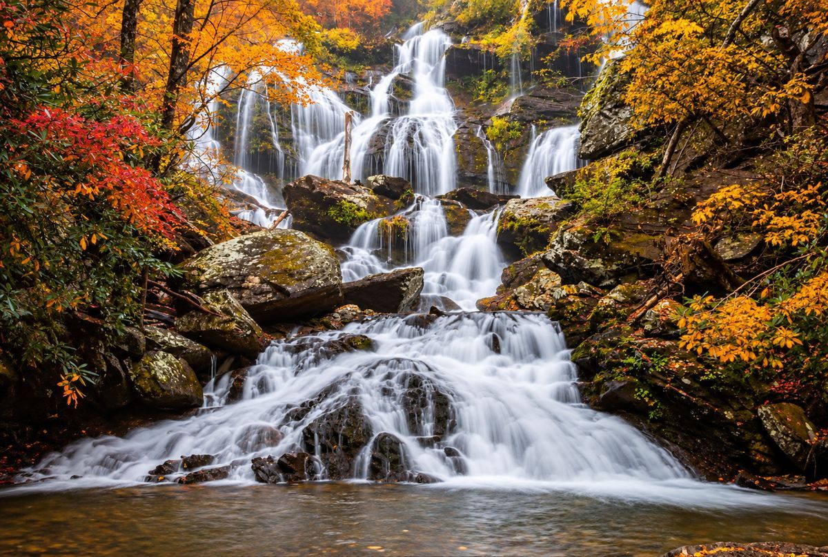 Catawba Falls cascading over rocky ledges surrounded by brilliant red, orange and golden fall foliage in Western North Carolina.