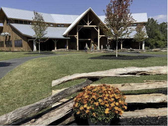 Jeter Mountain Farm near Hendersonville, North Carolina, featuring its large timber-frame barn, rustic fencing and colorful fall mums on a sunny autumn day.