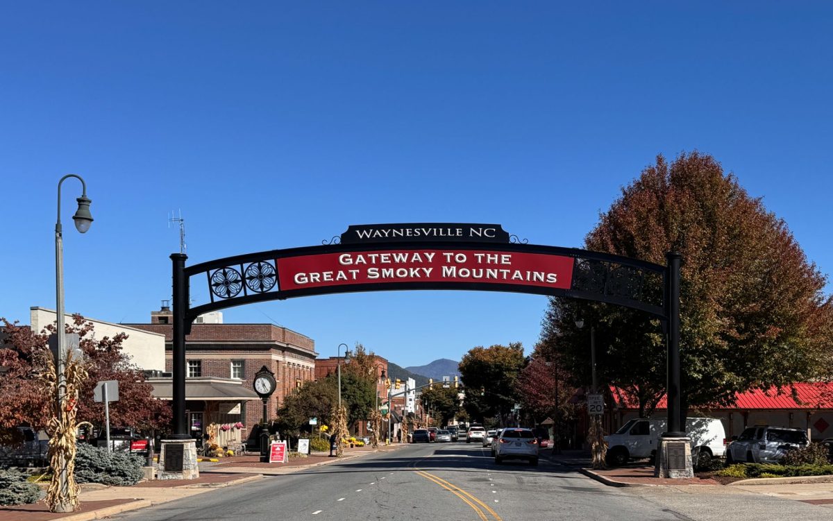 Downtown Waynesville, North Carolina, featuring the iconic Gateway to the Great Smoky Mountains arch over Main Street, with autumn foliage and mountain views in the distance.